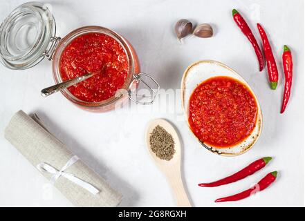 Sauce Harissa ou adjika sur fond blanc. Sauce au piment. Cuisine traditionnelle tunisienne, géorgienne et arabe. Vue de dessus, plan d'appartement. Banque D'Images