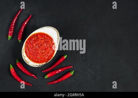 Sauce adjika aux piments chauds. Sauce Harissa dans un bol sur fond noir. Tunisie, cuisine géorgienne et arabe. Espace pour le texte. Vue de dessus, plat la Banque D'Images