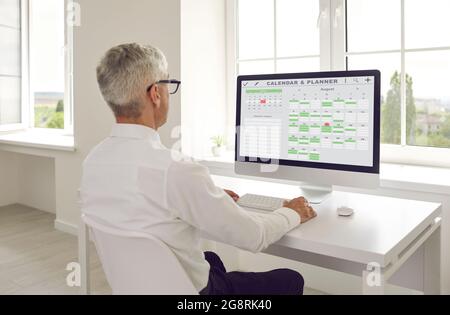 Le responsable senior organise l'horaire à l'aide du calendrier et du planificateur sur l'ordinateur du bureau Banque D'Images
