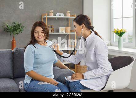 La femme médecin écoute le cœur et le souffle d'une jeune femme à travers un stéthoscope sur sa poitrine. Banque D'Images