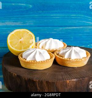 Petits gâteaux faits maison à tartiettes avec du caillé de citron et de la crème fouettée, fond blanc gris béton espace copie Banque D'Images