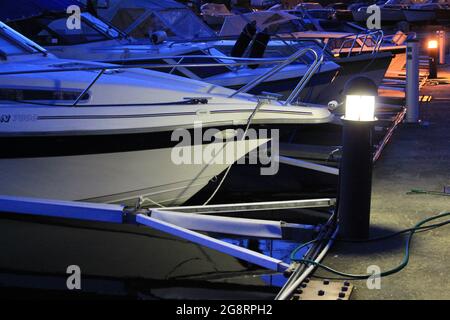 Yachts la nuit sur la jetée dans le port. Les lanternes sur la jetée illuminent les bateaux qui se trouvent dans le port. Banque D'Images