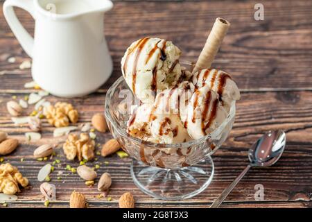 Glace Roma aux amandes, pistaches et noix dans un bol en verre avec sauce caramel. Banque D'Images