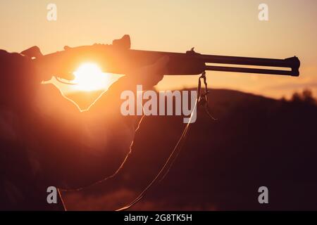 Déclencheur du fusil de chasse. Fusil Hunter silhoueté dans beau coucher de soleil. Silhouette du chasseur Banque D'Images