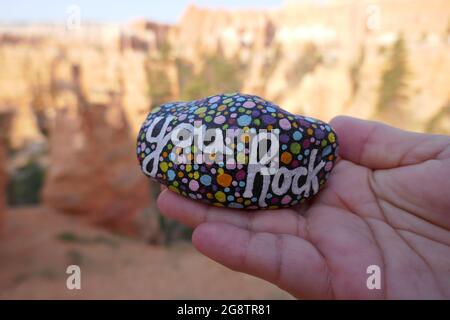 La gentillesse du rock avec le message de rock vous peint tenu à portée de main avec le Grand Canyon hors du foyer en arrière-plan Banque D'Images