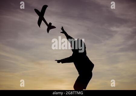 Enfant avec avion rêve de voyager en été dans la nature au coucher du soleil. Enfant actif jouant. Enfance à la campagne. Pilote aviateur enfant avec un jouet Banque D'Images