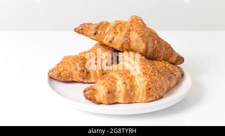 Assiette blanche avec trois croissants savoureux sur fond blanc. Cuisine française Banque D'Images