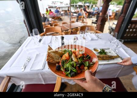 20 juillet 2021, Brandebourg, Potsdam : une salade de crevettes et de truite est servie au restaurant 'Kongsnaes - la gare impériale de Sailor'. Le restaurant Laggner Group, construit en bois norvégien, est situé sur la Jungfernsee. Il sert principalement du poisson, principalement régional, ainsi que de la bouillabaise et des plats de saison. En 1890, le Kaiser Wilhelm II fit reconstruire sa station de voile sur la Jungfernsee de Potsdam dans le style dragon 'norvégien'. Après un incendie dans les jours de guerre. En 1945, les fortifications frontalières de la RDA se sont encouru le long de ce site. Avec l'aide de plans historiques et de photographies, le reconst Banque D'Images