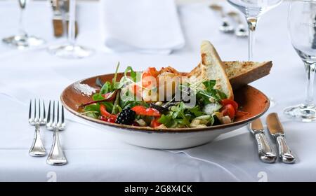 20 juillet 2021, Brandebourg, Potsdam : une salade avec crevettes est posée sur une table au restaurant 'Kongsnaes - la gare impériale de Sailor'. Le restaurant Laggner Group, construit en bois norvégien, est situé sur la Jungfernsee. Il sert principalement du poisson, principalement régional, ainsi que de la bouillabaise et des plats de saison. En 1890, le Kaiser Wilhelm II fit reconstruire sa station de voile sur la Jungfernsee de Potsdam dans le style dragon 'norvégien'. Après un incendie dans les jours de guerre. En 1945, les fortifications frontalières de la RDA se sont encouru le long de ce site. Avec l'aide de plans historiques et de photographies, le reco Banque D'Images