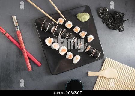 Saumon sushi sur table noire avec baguettes Banque D'Images