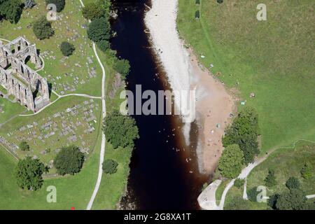 Vue aérienne de l'abbaye de Bolton avec bains de soleil et baignade dans la rivière Wharfe Banque D'Images