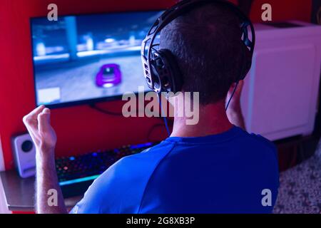 Jeune homme avec un casque jouant à des jeux vidéo sur un ordinateur de jeu Banque D'Images