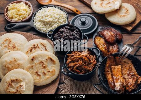 Table servie avec le petit déjeuner vénézuélien, arepas avec différents types de garnitures telles que les haricots noirs, la viande déchiquetée, plantain frit et le fromage Banque D'Images