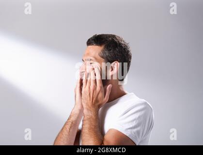 Homme utilisant une huile du visage pour se masser dans sa peau. Banque D'Images