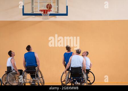 Les vétérans de la guerre des handicapés affrontent des équipes de basket-ball en fauteuil roulant photographiées en action tout en jouant un match important dans une salle moderne. Banque D'Images