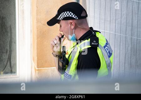 Glasgow, Écosse, Royaume-Uni. 22 juillet 2021. PHOTO : un policier écossais est vu sur le terrain pour parler d'une bouffée sournoise sur une E-cigarette pendant son travail, Vu d'un appartement à Parnie St. le tournage du nouveau film Indiana Jones 5 au milieu du centre-ville de Glasgow s'est déplacé dans le quartier de la ville marchande alors que le superproduction hollywoodienne a établi Glasgow comme une Amérique des années 1950/1960. Les acteurs acteurs de cinéma, de premier plan et de soutien, ainsi que l'équipe de production, les réalisateurs et les coureurs, peuvent être vus sur et en dehors du tournage. Crédit : Colin Fisher Banque D'Images