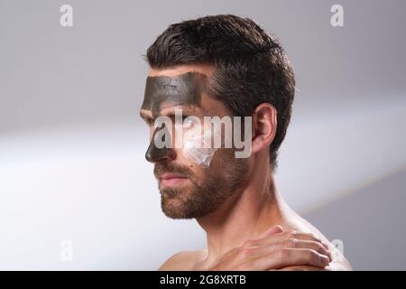 Homme utilisant des produits du visage sur sa peau. Masques pour le visage. Masques rajeunissants et hydratant. Banque D'Images