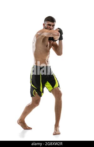 Un homme, un boxeur professionnel MMA mâle en mouvement isolé sur fond blanc de studio. Faire des combats musculaires d'athlète caucasien. Banque D'Images