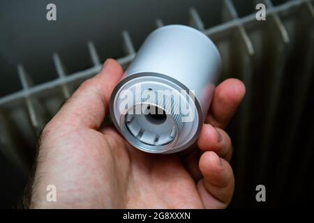 Main mâle POV montrant la tête thermostatique du radiateur connectée moderne Banque D'Images