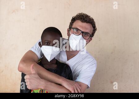 Dans cette image, un médecin blanc qui se porte volontaire dans un hôpital africain embrasse un petit garçon noir et un signe de pouce après avoir réussi un Banque D'Images