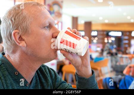 Surgut, Russie - 01.25.2020: Un homme boit du café dans une tasse de papier en KFC Banque D'Images