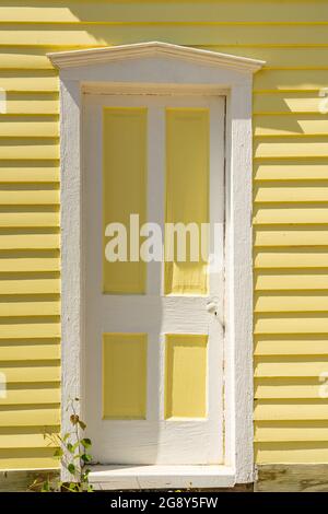 Ancienne porte blanche et jaune à l'extérieur de la maison en panneaux de clopboard Banque D'Images