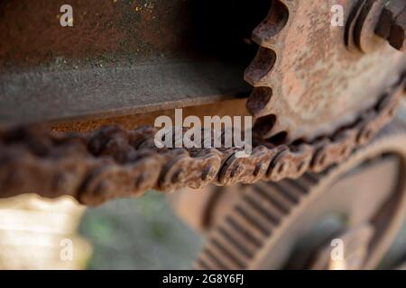 Détails rouillés des vieilles voitures abandonnées. Les pignons, les chaînes et les poulies rouillent dans l'ouverture. Pièces métalliques recouvertes de mousse de machines agricoles. Banque D'Images