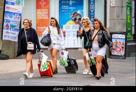 Dundee, Tayside, Écosse, Royaume-Uni. 23 juillet 2021. Météo au Royaume-Uni : une journée humide et couvert avec des sorts lumineux à travers le nord-est de l'Écosse avec des températures atteignant 21°C. Le confinement de Covid-19 s'est abaissé jusqu'au niveau zéro, les résidents locaux étant heureux de se rendre à l'extérieur pour s'amuser et profiter du temps d'été à Dundee. De jeunes femmes joyeuses et à la mode qui marchent ensemble des valises en roue dans le centre-ville. Crédit : Dundee Photographics/Alamy Live News Banque D'Images