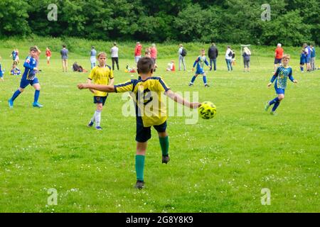 Arrière joueur de l'équipe de garçon kick kicks kicking ball les équipes de garçons jouent au football le samedi matin au Royaume-Uni Grande-Bretagne 2021 KATHY DEWITT Banque D'Images