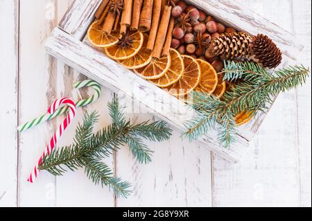 Composition de Noël. Arrangement des oranges sèches, des bâtons de cannelle, des étoiles anis et des noix dans une boîte. Branches d'arbre de fourrure et cannes de bonbons sur le backgro en bois Banque D'Images