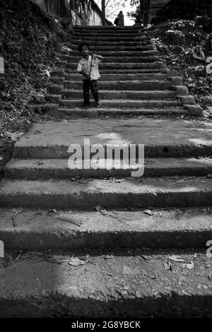 Un garçon jouant seul sur les escaliers. Cette image a été capturée le 13 janvier 2018, à Dhamrai, au Bangladesh, en Asie du Sud Banque D'Images