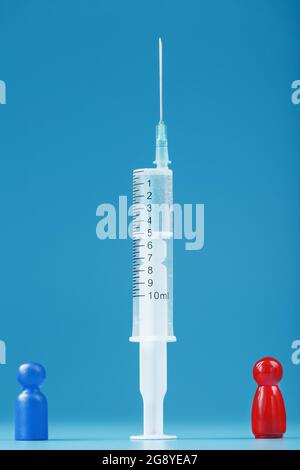 Miniature d'un homme bleu et rouge entre une seringue avec un vaccin. Le concept du conflit de vaccination et d'anti-vaccination. Avantages et inconvénients de Banque D'Images