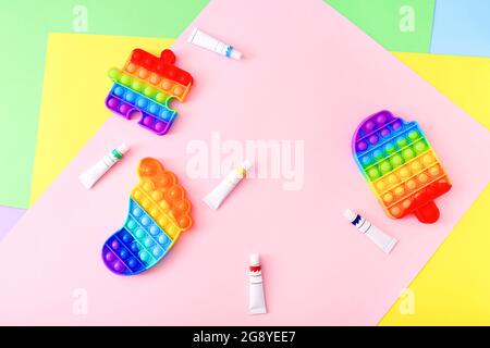 Nouveaux jouets tendance populaires en silicone coloré anti stress Pop IT pour enfants et peintures sur fond coloré. Banque D'Images