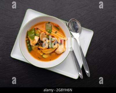 Curry thaï rouge épicé avec poulet et légumes dans un bol, vue du dessus Banque D'Images