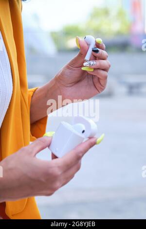 Femme d'affaires non reconnaissable portant une veste de costume jaune tenant un casque sans fil. Banque D'Images