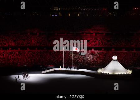 Stade national olympique, Tokyo, Japon. 23 juillet 2021. Les feux d'artifice et les feux clignotants ont grimpé au-dessus du nouveau stade olympique de Tokyo vendredi, alors que les Jeux d'été 2020 retardés ont finalement tenu leur cérémonie d'ouverture culminant avec l'éclairage du chaudron olympique. Les athlètes ont défilé devant des sièges essentiellement vides, avec seulement une foule clairsemée admise en raison des restrictions de la COVID-19. Le drapeau japonais est élevé au son de l'hymne national, lors de la cérémonie d'ouverture des Jeux Olympiques de Tokyo en 2020, dans le Stade Olympique crédit: Action plus Sports/Alamy Live News Banque D'Images