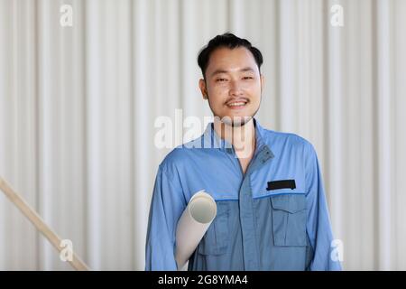 Portrait d'un ingénieur de sexe masculin, avec confiance en soi et de manière amicale, tenant le papier en rouleau Banque D'Images