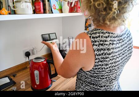 Femme d'âge moyen regardant le British Gas Smart Meter dans la cuisine Banque D'Images