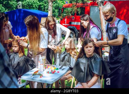 Zaporizhia, Ukraine- 19 juin 2021: Fête de la famille de charité: Garçons et filles participant à l'atelier de coiffage en plein air. Jeunes coiffeurs à wor Banque D'Images