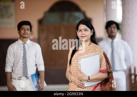 Professeur d'école indien souriant et confiant avec des élèves en arrière-plan Banque D'Images