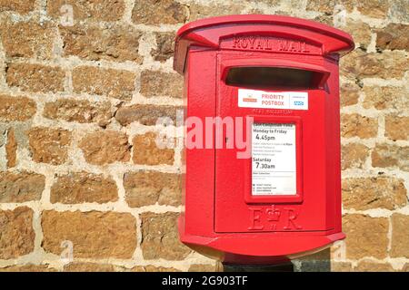 Boîte postale prioritaire rouge royale sur un mur dans le village anglais de Rockingham, en Angleterre. Banque D'Images