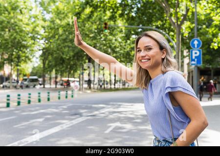 Une jeune femme souriante salue le taxi dans la rue Banque D'Images