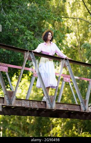 Jeune femme debout sur la passerelle dans la campagne qui regarde loin Banque D'Images