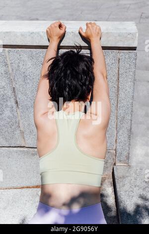 Jeune femme avec les bras levés faisant de l'exercice d'étirement tout en  étant assis pieds croisés à la maison Photo Stock - Alamy