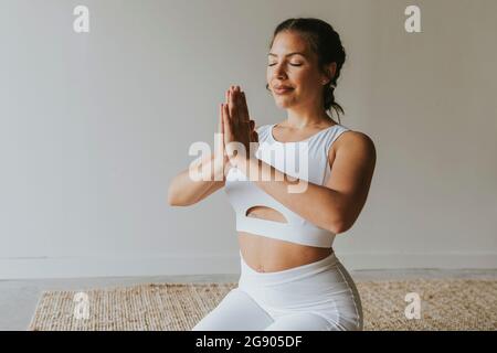 Instructeur de fitness féminin avec les mains jointes méditant au studio de yoga Banque D'Images