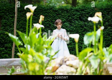 Fille en robe de communion blanche avec appareil photo au parc Banque D'Images