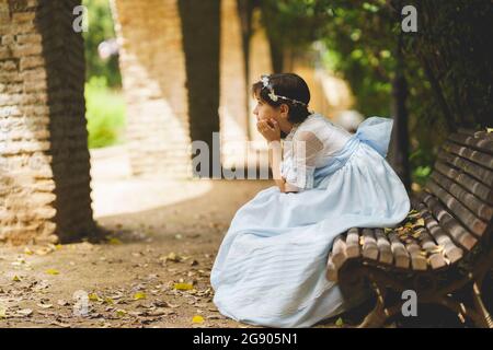 Fille avec la main sur le menton contemplant tout en étant assis sur le banc Banque D'Images