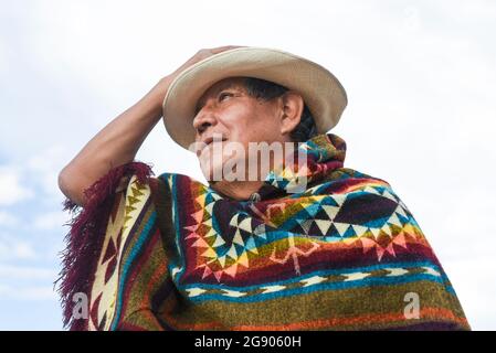 Homme senior portant un poncho et un chapeau tout en regardant loin Banque D'Images