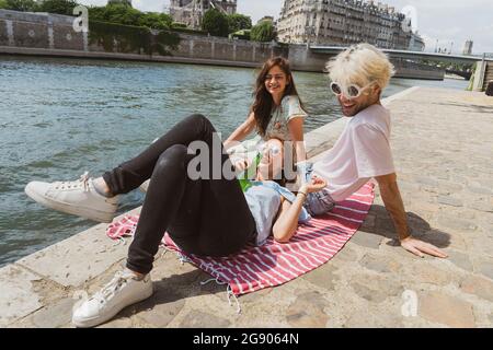 Femme avec une bouteille de bière couché sur un tour d'homme assis par une amie femelle sur la promenade Banque D'Images