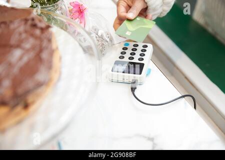 Femme adulte de taille moyenne effectuant un paiement sans contact par carte de crédit au café Banque D'Images